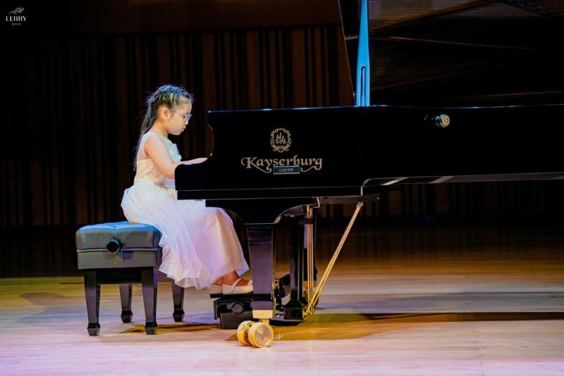 Một người đang chăm chú đọc sheet nhạc piano và đặt tay lên phím đàn, thể hiện quá trình học và luyện tập theo bản nhạc