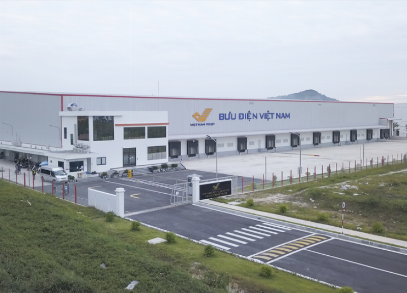 Hình ảnh minh họa các loại chứng từ xuất nhập khẩu (vận đơn, hóa đơn...) được dán nhãn địa chỉ có kèm mã bưu chính Vĩnh Phúc, đặt cạnh một mô hình tàu container hoặc xe tải logistics.