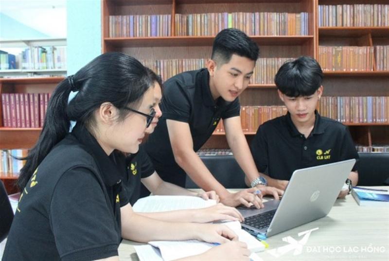 Một sinh viên đang ngồi tập trung ôn tập luật doanh nghiệp với sách vở và máy tính.